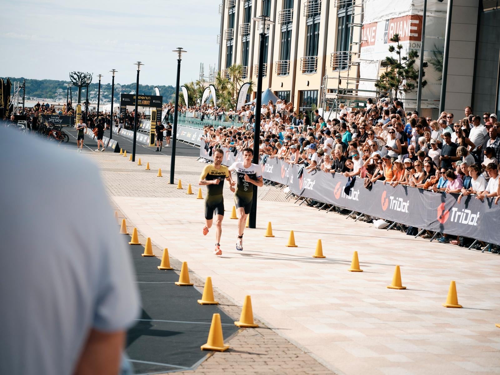 Athletes running down the finish chute lined with spectators at supertri Jersey