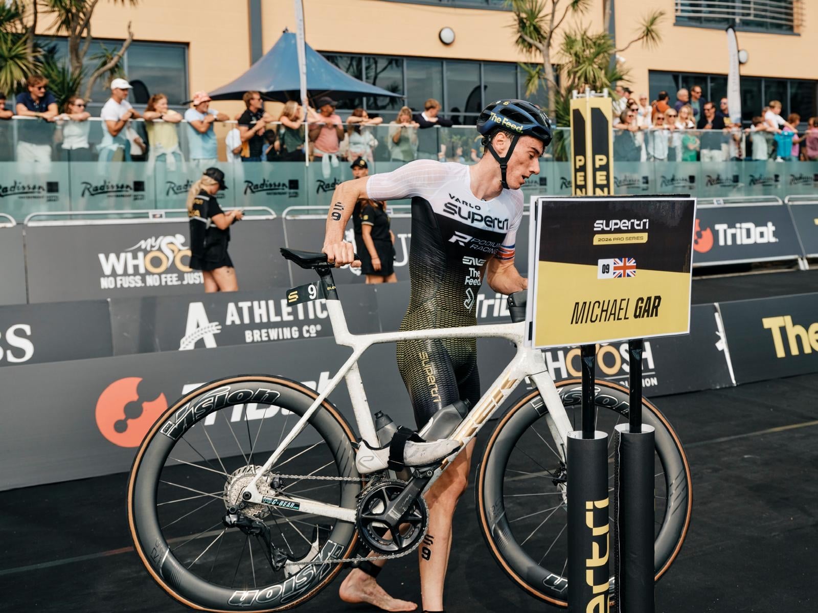 Michael Gar at his bike rack beside his name board at supertri Jersey